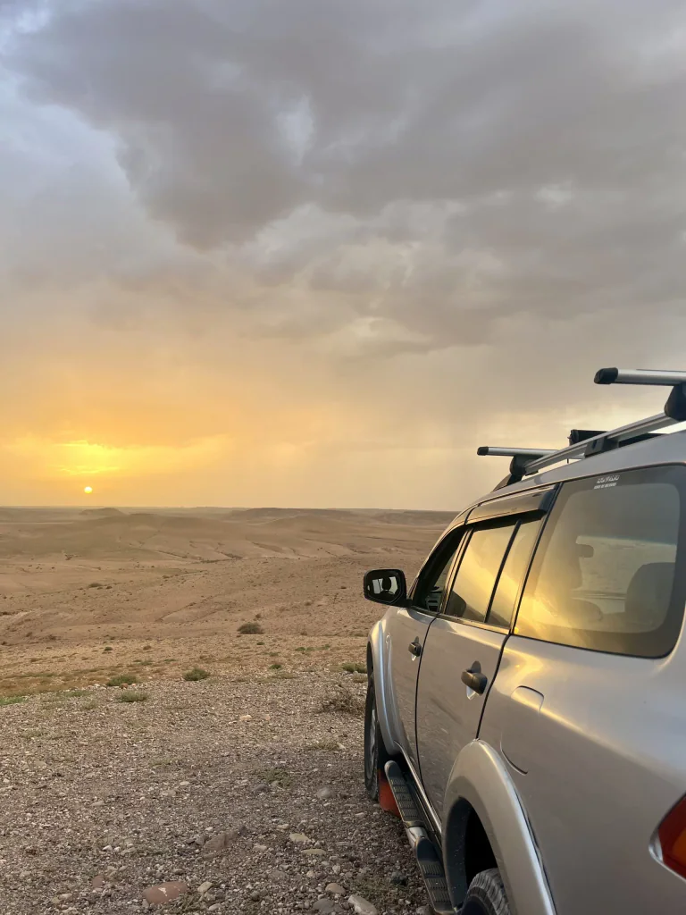 Vehículo de ruta junto al paisaje desértico al atardecer